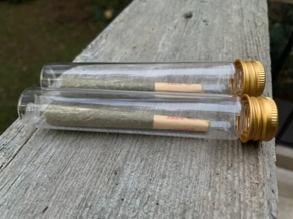 Image of two hemp pre-rolls in glass tubes on wooden a surface