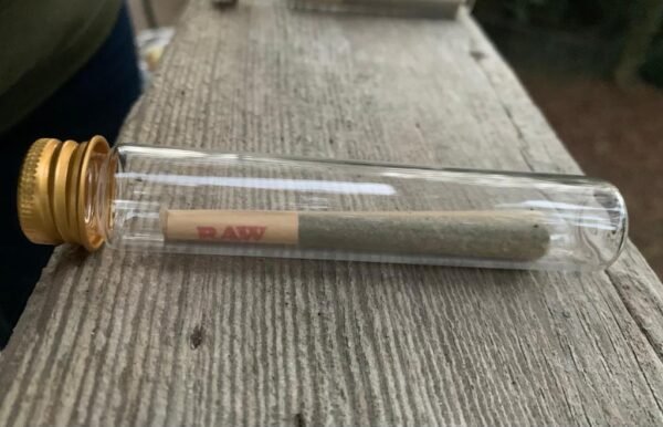 image of a hemp pre-roll in a glass tube on a wooden surface